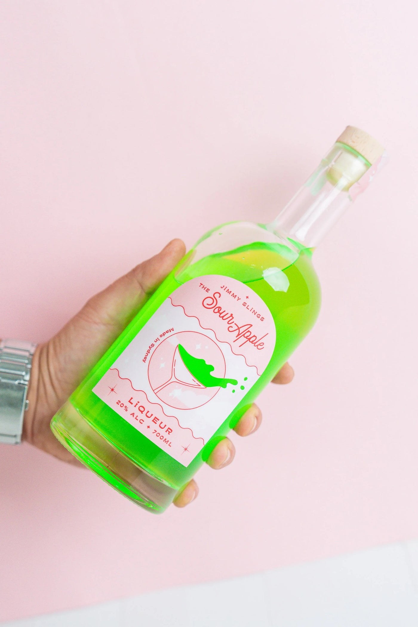 The Greenbach sour apple bottle in its pink world